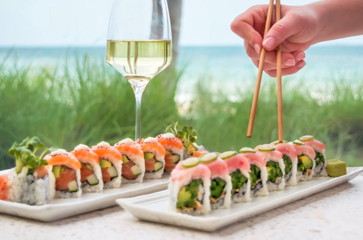sushi, a glass of wine, and a hand holding chopsticks